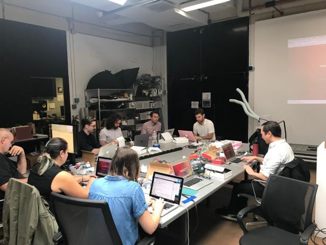 Groups of people sit around conference room table