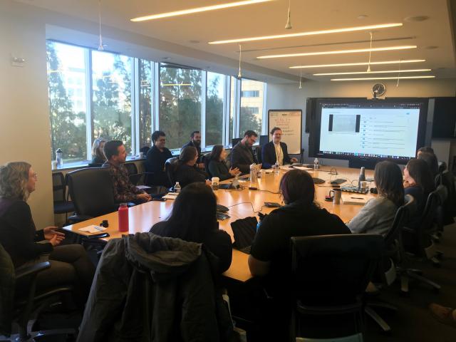 Staff sit around a conference room table looking at a computer monitor